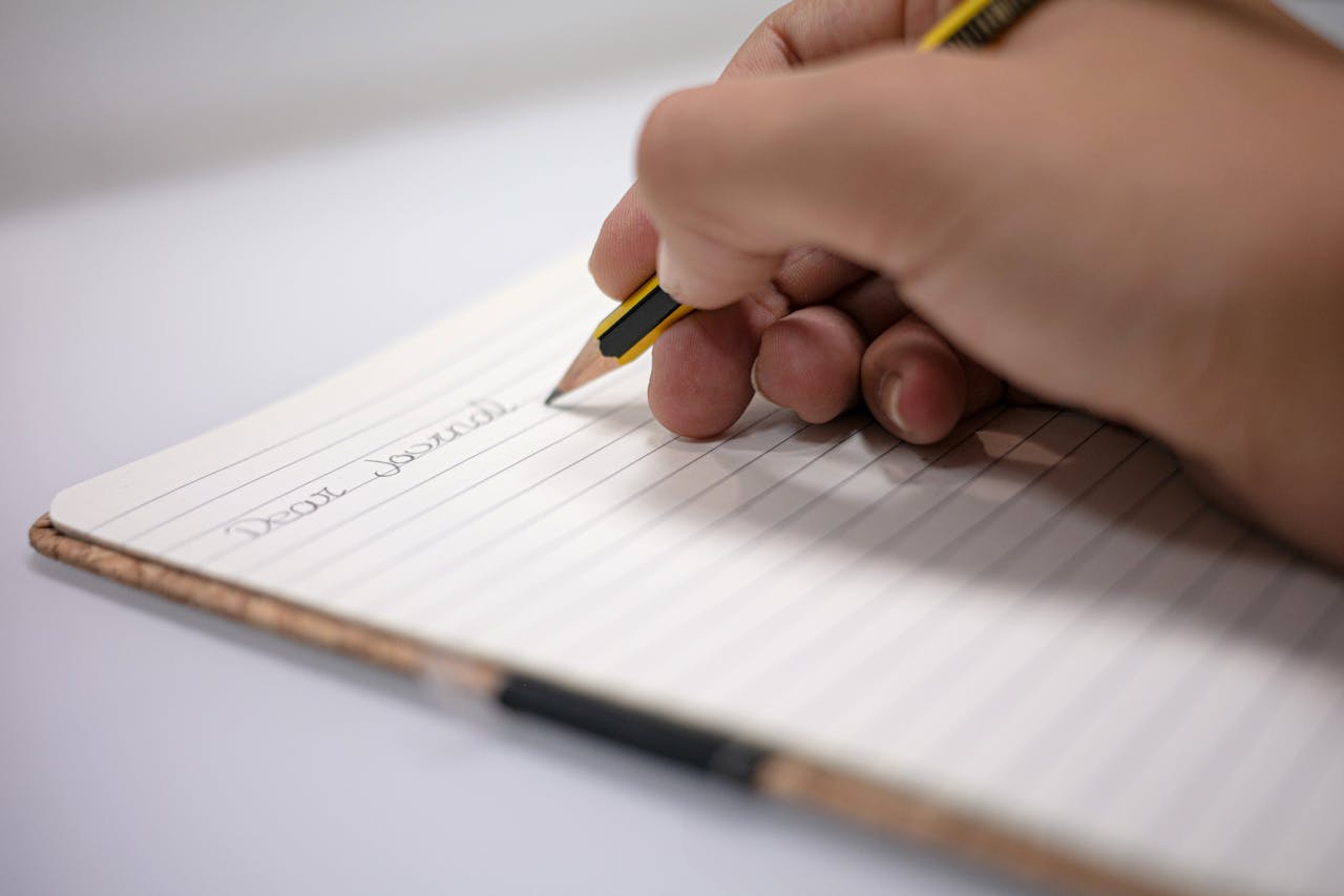 Close-up of a hand writing with a pencil in a notebook. Perfect for educational and writing themes.
